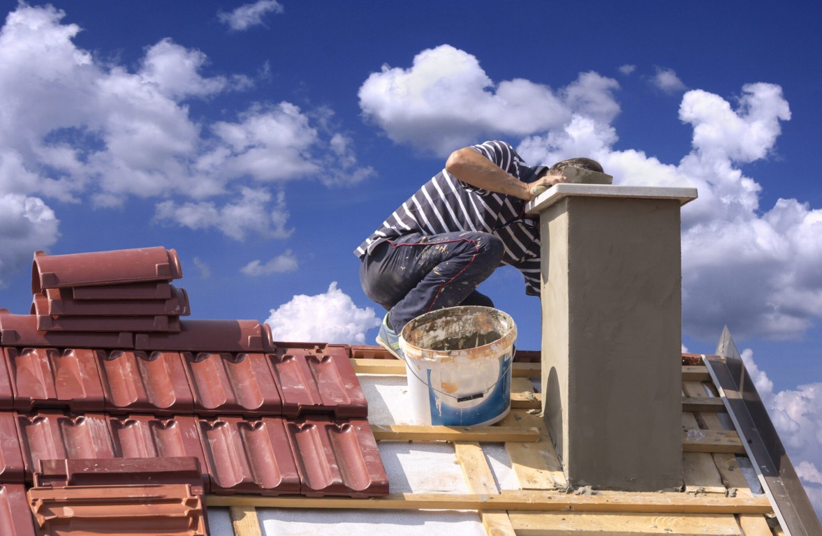 Masonry contractor repairing residential chimney on rooftop in Temecula, CA